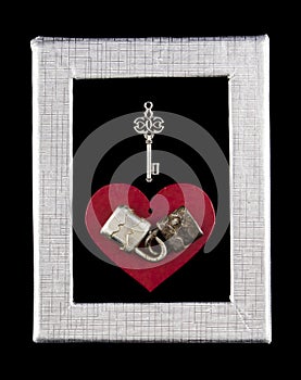 Two connected padlocks on the background of a red heart with a key in a silver frame