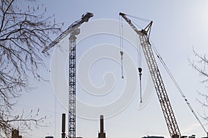 Two construction cranes on the blue sky background