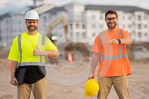 Two construction site workers in helmet work outdoors. Builders workers working on construction site. The job of a