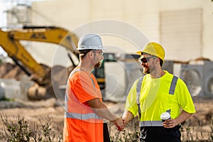 Two construction site workers in helmet work outdoors. Builders workers working on construction site. The job of a