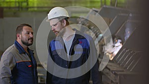 Two construction workers discuss stages of construction in heavy industry factory