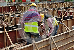 Two construction workers fabricating ground beam formwork