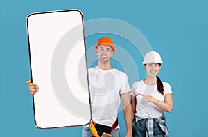 Two Construction Workers In Helmet Holding Showing Big Cellphone Screen