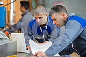 two construction workers holding plans discussing project