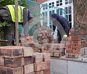 Two construction workers laying bricks as part of a renovation of an Edwardian suburban house in north London, UK