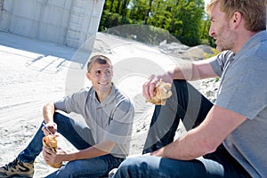 two construction workers taking break on site eating lunch