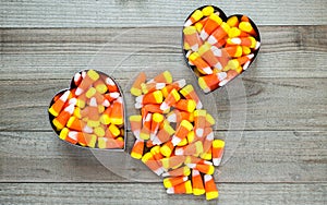 Two cookie cutters overflowing with candy corn on wood background