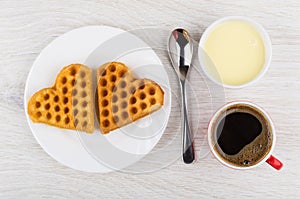 Two cookies, coffee in cup, bowl with condensed milk, spoon