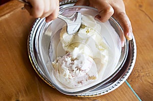 Two coop of ice cream in transparent glass bowl. Child eats frozen yogurt in summer caffe. Fingers and spoon. Homemade