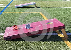Two cornhole games with beanbags on a turf field