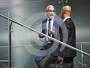 Two corporate executives talking while ascending stairs