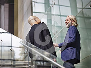 Two corporate executives talking while ascending stairs