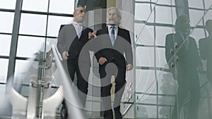 Two corporate executives talking while descending stairs