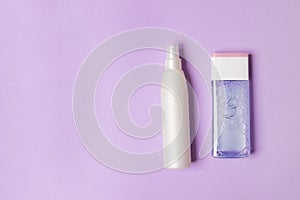 Two cosmetic bottles on purple colored paper background with copy space