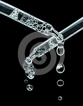 Two cosmetic dropper with bubbles close-up on a black background. Glowing pipettes in the dark photo