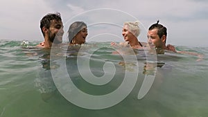 Two couple of friends having fun swimming in sea action camera pov of young playful people group together on beach