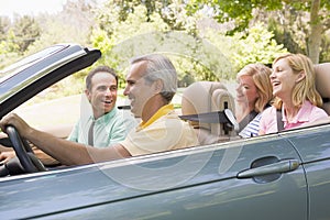 Two couples in convertible car smiling