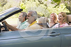 Two couples in convertible car smiling