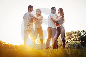 Two couples dancing kizomba during sunset in a park