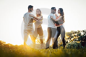 Two couples dancing kizomba during sunset in a park