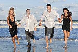 Two Couples, Having Fun Running At The Beach