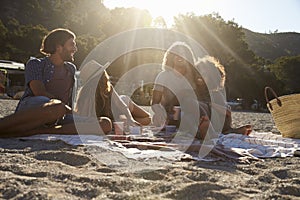 Two couples having a picnic on the beach, backlit, close up