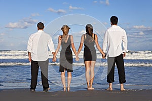 Two Couples, Holding Hands On A Beach