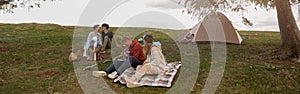 Two couples resting and having fun on top of mountain at tent. Camping concept.
