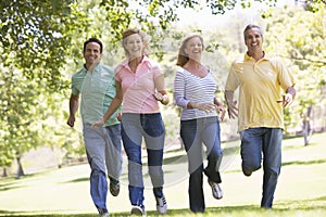 Two couples running outdoors smiling