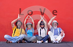 Two couples, senior and middle aged, trying to write the word love with hands. dressed with colorful suspenders, bow ties and