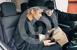 Two couriers sitting in van checking information on box for delivery