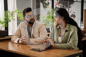 Two coworkers discussing business details while sitting in modern office space