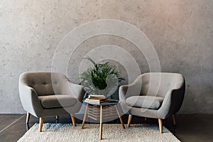 Two cozy grey armchairs standing on white carpet