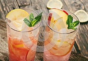Two cranberry cocktail with ice, mint, lemon and apple photo