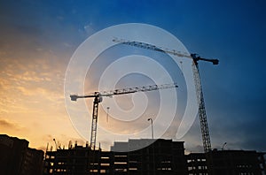 Two cranes on sunset construction site