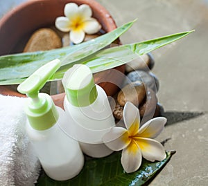 Two cream tubes and towel. Flowers and stones spa concept.