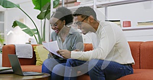 Two creative businesspeople celebrating a success while using a laptop and reading paperwork in the office. Colleagues