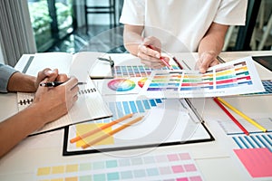 Two creative graphic designer team working on color selection and drawing on graphic tablet, Color swatch samples chart for