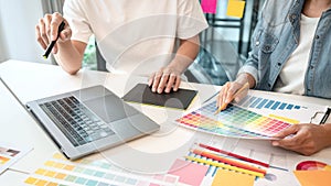 Two creative graphic designer team working on color selection and drawing on graphic tablet, Color swatch samples chart for