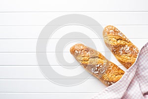 Two crispy fresh baguettes on white table
