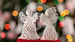Two crocheted xmas angels spinning in front of christmas tree