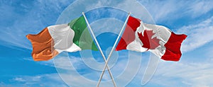 two crossed flags canada and Ireland waving in wind at cloudy sky. Concept of relationship, dialog, travelling between two