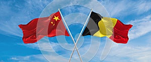 two crossed flags china and Belgium waving in wind at cloudy sky. Concept of relationship, dialog, travelling between two