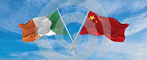 two crossed flags china and Ireland waving in wind at cloudy sky. Concept of relationship, dialog, travelling between two