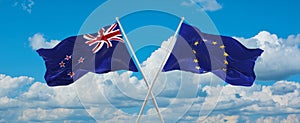 two crossed flags The European Union and New Zealand waving in wind at cloudy sky. Concept of relationship, dialog, travelling