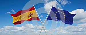 two crossed flags The European Union and spain waving in wind at cloudy sky. Concept of relationship, dialog, travelling between