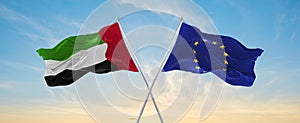 two crossed flags The European Union and United Arab Emirates waving in wind at cloudy sky. Concept of relationship, dialog,