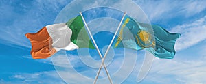 two crossed flags Kazakhstan and Ireland waving in wind at cloudy sky. Concept of relationship, dialog, travelling between two