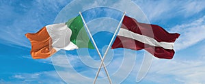 two crossed flags latvia and Ireland waving in wind at cloudy sky. Concept of relationship, dialog, travelling between two