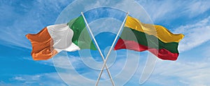 two crossed flags LITHUANIA and Ireland waving in wind at cloudy sky. Concept of relationship, dialog, travelling between two